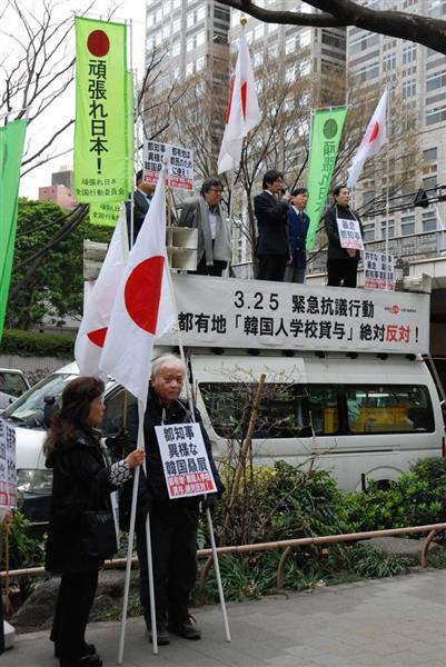東京都が都有地を韓国学校の増設用地として貸与することに「絶対反対」のプラカードを掲げ声を上げる人たち＝２５日午後、東京都新宿区の都庁前